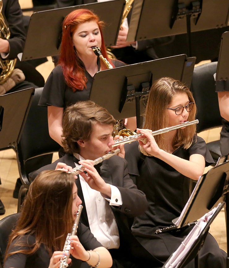 Male and female students playing their assortment of woodwind instruments onstage at Carnegie Male and female students playing their assortment of woodwind instruments onstage at Carnegie